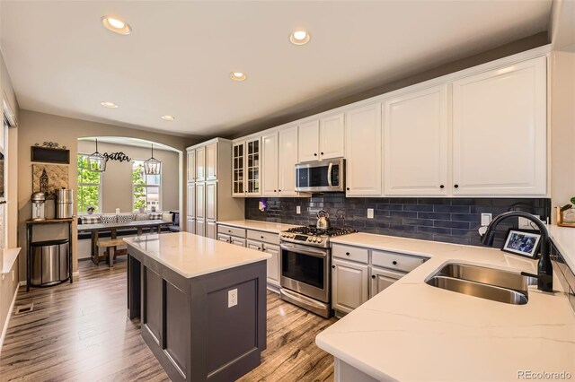 10694 Cedarcrest Cir, Highlands Ranch, CO 80130 - kitchen with appliances with stainless steel finishes, a sink, arched walkways, white cabinetry, and recessed lighting