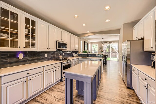 10694 Cedarcrest Cir, Highlands Ranch, CO 80130 - kitchen featuring appliances with stainless steel finishes, a peninsula, arched walkways, recessed lighting, and light wood-style floors