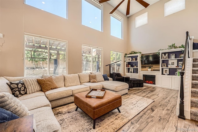 10694 Cedarcrest Cir, Highlands Ranch, CO 80130 - living area with a towering ceiling, light wood-style floors, a lit fireplace, stairs, and a ceiling fan