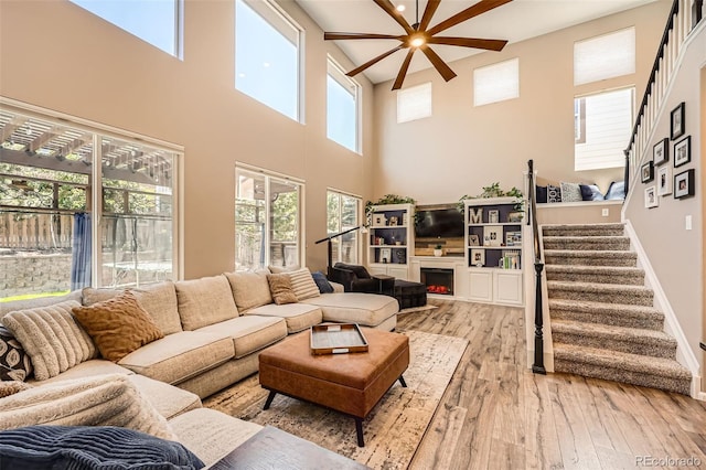 10694 Cedarcrest Cir, Highlands Ranch, CO 80130 - living area with a ceiling fan, light wood finished floors, a towering ceiling, stairway, and baseboards