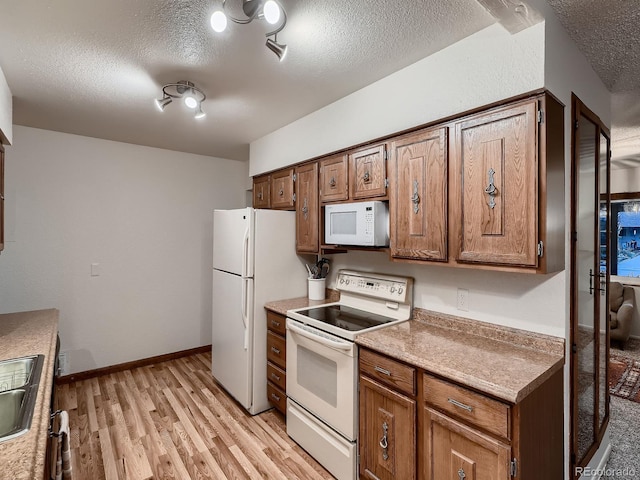 7112 S Platte Canyon Dr, Littleton, CO 80128 - kitchen featuring white appliances, light wood finished floors, a textured ceiling, light countertops, and a sink