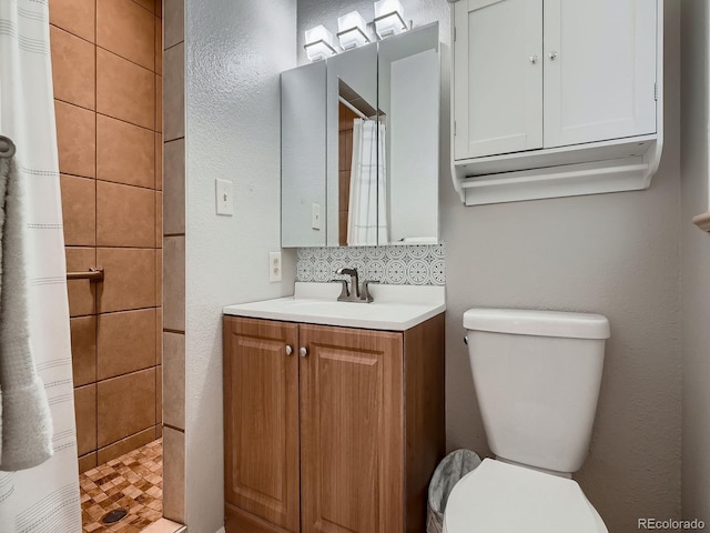 7112 S Platte Canyon Dr, Littleton, CO 80128 - full bathroom featuring toilet, vanity, a tile shower, and backsplash