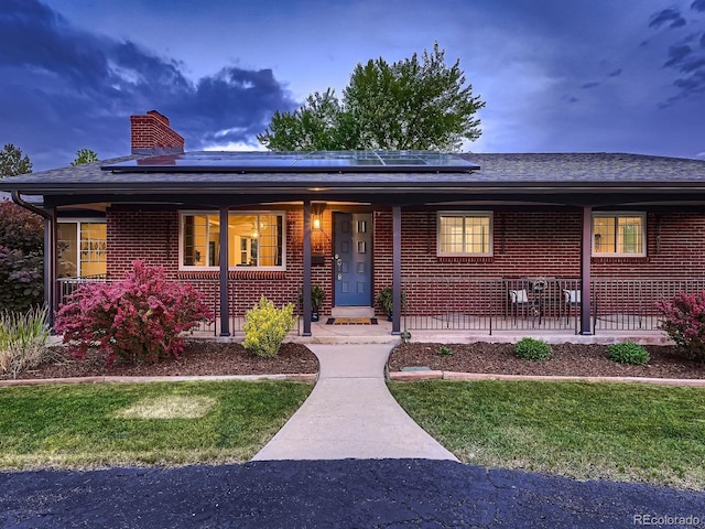 7112 S Platte Canyon Dr, Littleton, CO 80128 - ranch-style house with a porch, brick siding, roof mounted solar panels, and a chimney