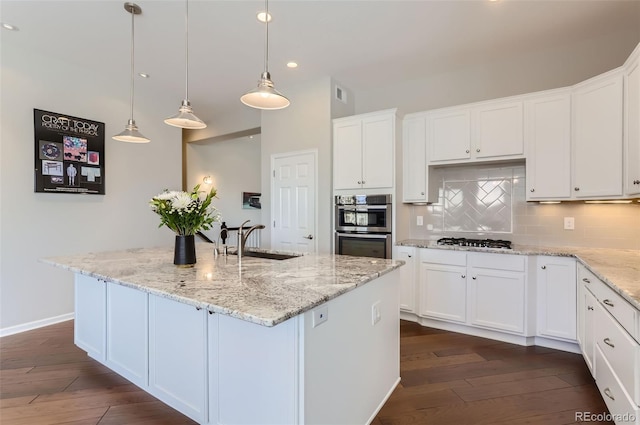 kitchen featuring sink, white cabinets, an island with sink, and decorative light fixtures