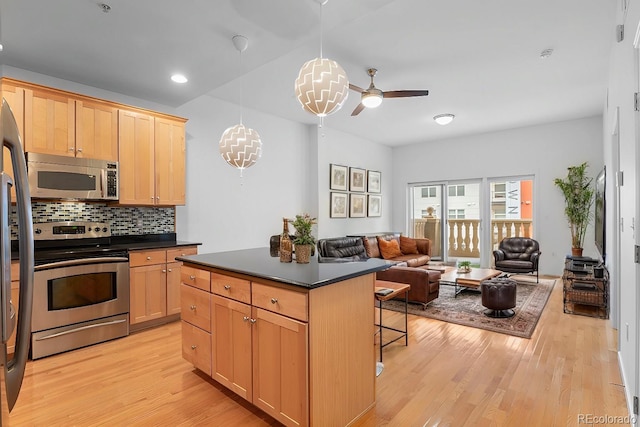 kitchen with light wood-type flooring, stainless steel appliances, a kitchen breakfast bar, and dark countertops