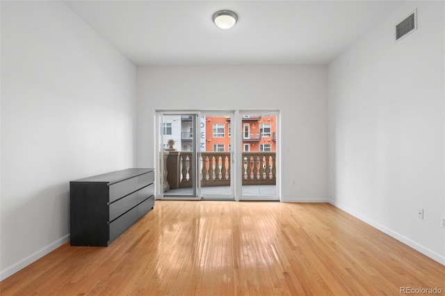 empty room featuring visible vents, baseboards, and wood-type flooring