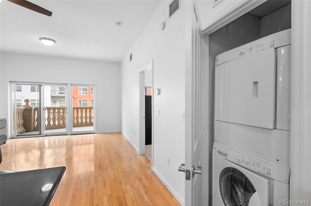 laundry area featuring light wood-type flooring, visible vents, stacked washing maching and dryer, baseboards, and laundry area