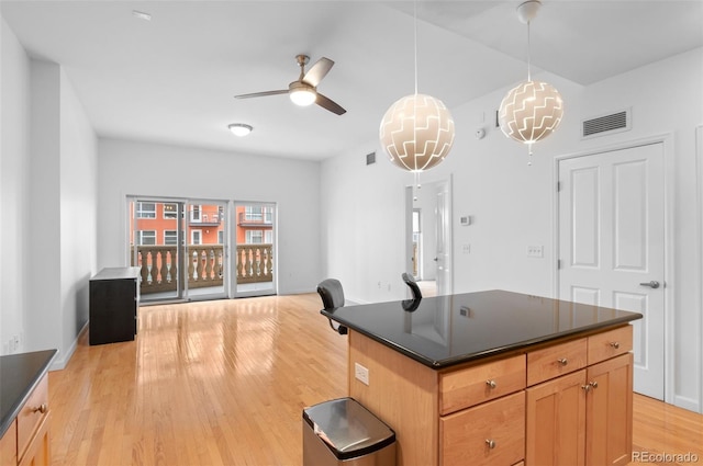 kitchen with dark countertops, visible vents, light wood finished floors, and pendant lighting