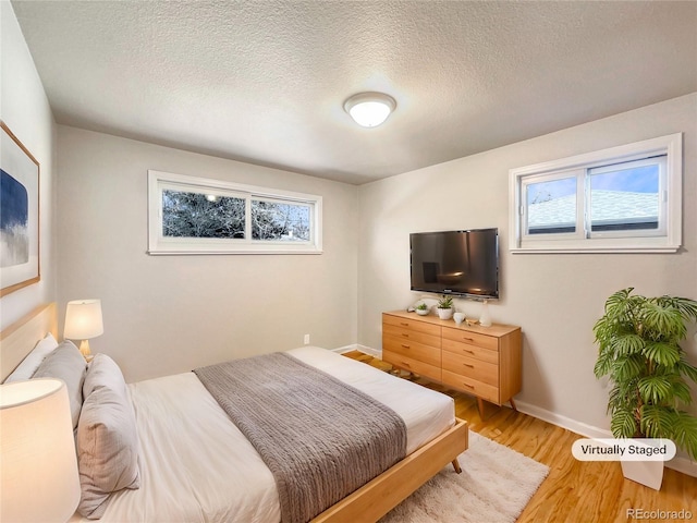 bedroom with wood-type flooring, a textured ceiling, and multiple windows