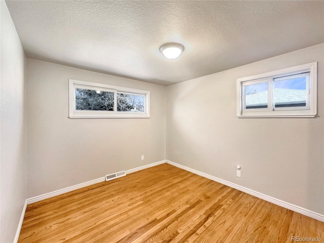 empty room with light hardwood / wood-style flooring, a healthy amount of sunlight, and a textured ceiling