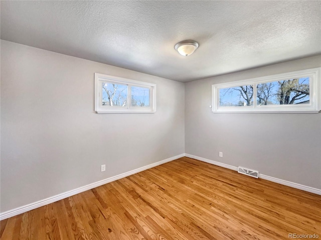 spare room with a textured ceiling and light wood-type flooring