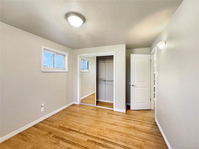 unfurnished bedroom featuring light hardwood / wood-style floors, a textured ceiling, and a closet