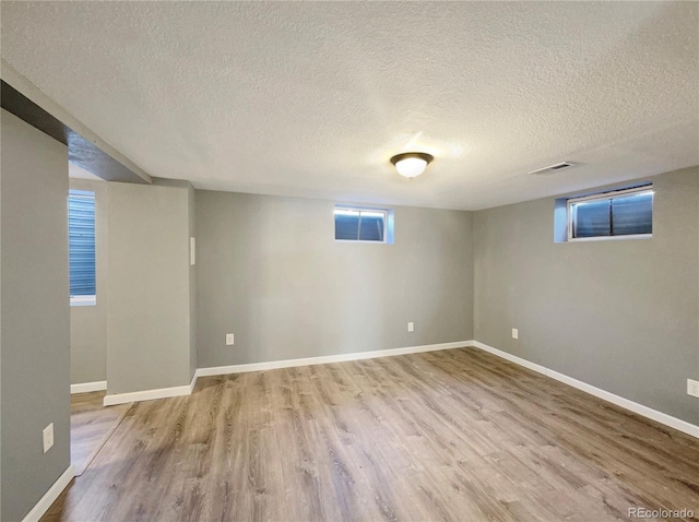 basement featuring a textured ceiling and light wood-type flooring