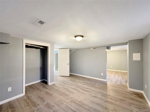 unfurnished bedroom featuring a textured ceiling, light hardwood / wood-style flooring, and a closet