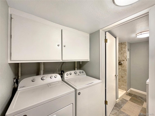 clothes washing area featuring cabinets, a textured ceiling, and separate washer and dryer