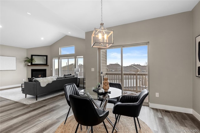 dining room featuring hardwood / wood-style flooring, vaulted ceiling, and a notable chandelier