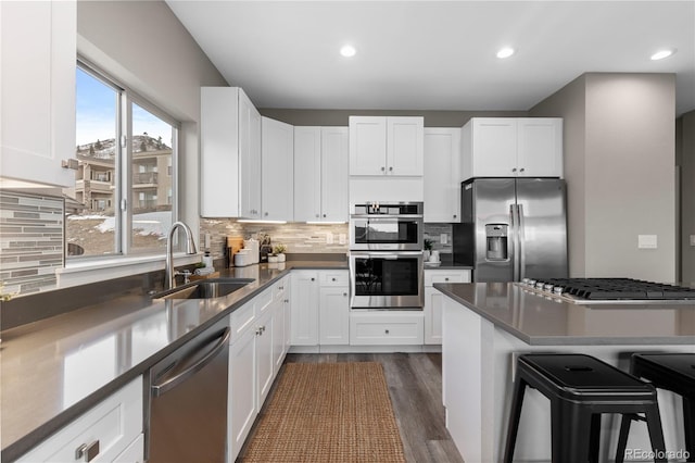 kitchen featuring sink, stainless steel appliances, white cabinets, and a kitchen bar