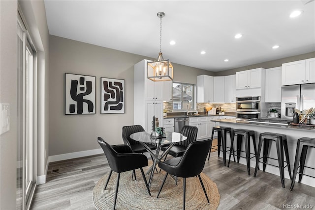 dining room with wood-type flooring, sink, and an inviting chandelier