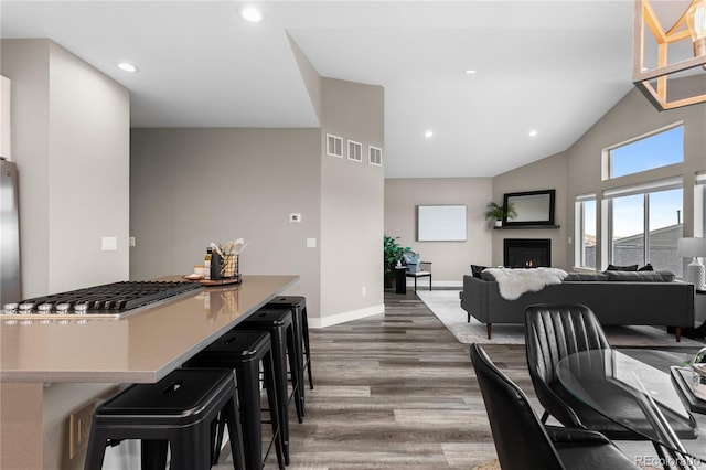 interior space with a breakfast bar area, high vaulted ceiling, and dark hardwood / wood-style floors