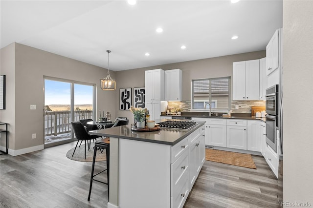 kitchen featuring a kitchen island, decorative light fixtures, sink, white cabinets, and a kitchen breakfast bar