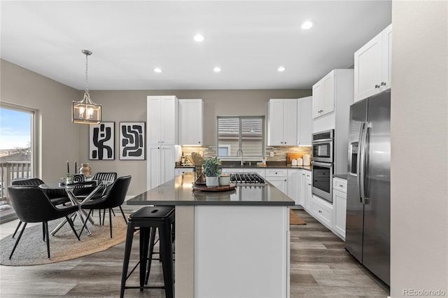 kitchen with white cabinetry, a kitchen island, a kitchen breakfast bar, and appliances with stainless steel finishes