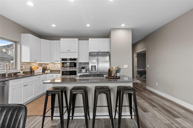 kitchen featuring stainless steel appliances, sink, a breakfast bar area, and white cabinets