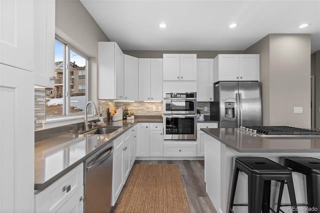 kitchen with white cabinetry, appliances with stainless steel finishes, sink, and a breakfast bar area