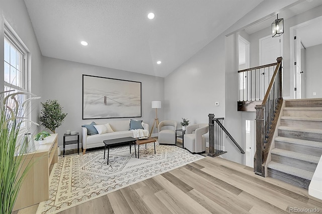 living room with vaulted ceiling, a textured ceiling, and light hardwood / wood-style flooring