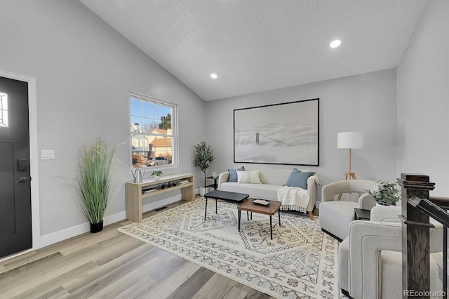 living room with high vaulted ceiling, a textured ceiling, and light hardwood / wood-style flooring