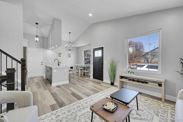 living room featuring lofted ceiling, sink, a textured ceiling, and light hardwood / wood-style floors