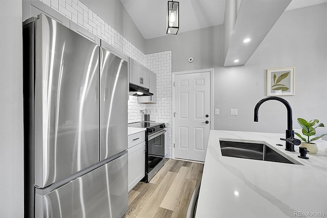 kitchen with sink, stainless steel appliances, light stone counters, white cabinets, and decorative light fixtures