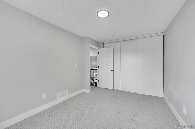 unfurnished bedroom with carpet floors, a textured ceiling, and a closet