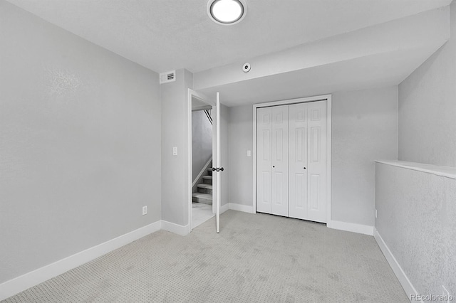 unfurnished bedroom with light colored carpet and a closet