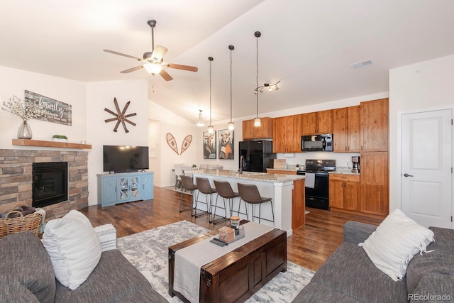 living room featuring ceiling fan, a stone fireplace, lofted ceiling, and dark hardwood / wood-style floors