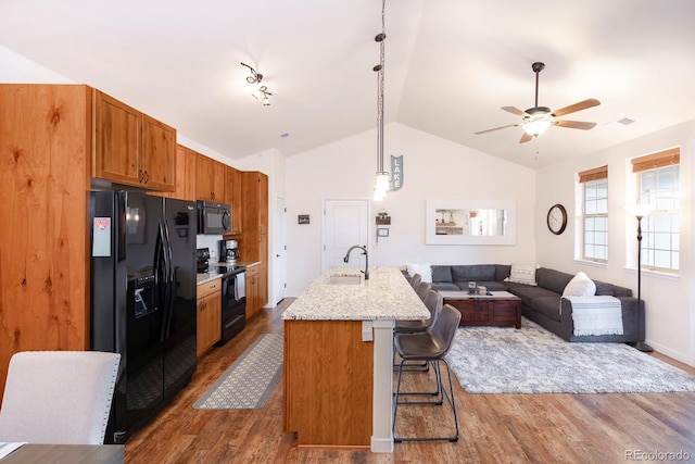 kitchen featuring a breakfast bar area, lofted ceiling, black appliances, and dark wood-type flooring