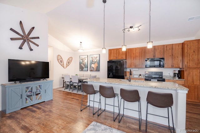 kitchen featuring wood-type flooring, black appliances, and lofted ceiling