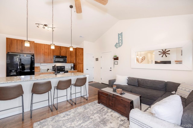 living room with light hardwood / wood-style floors, high vaulted ceiling, and ceiling fan