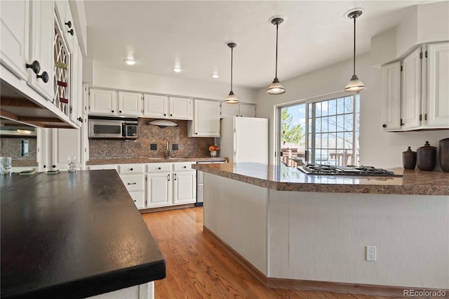 6492 S Piney Creek Cir, Centennial, CO 80016 - kitchen with a peninsula, a sink, backsplash, light wood-style floors, and appliances with stainless steel finishes