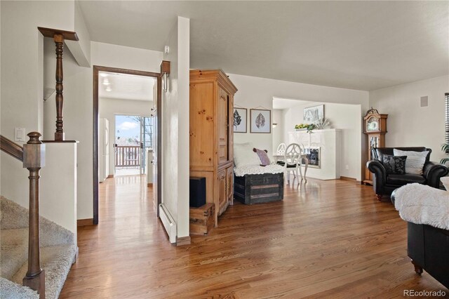 6492 S Piney Creek Cir, Centennial, CO 80016 - living area featuring baseboards, baseboard heating, wood finished floors, and stairs