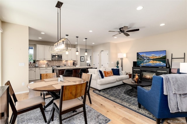8186 E 53rd Dr, Denver, CO 80238 - dining room featuring light wood-style floors, recessed lighting, a ceiling fan, and a glass covered fireplace