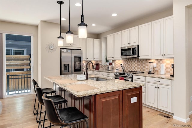 8186 E 53rd Dr, Denver, CO 80238 - kitchen with stainless steel appliances, light wood-style floors, backsplash, white cabinetry, and recessed lighting