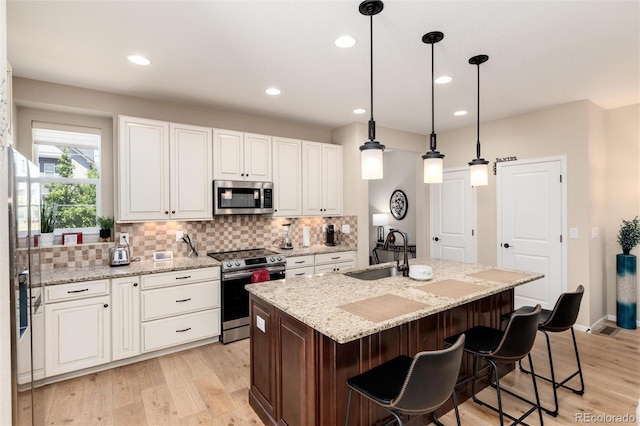 8186 E 53rd Dr, Denver, CO 80238 - kitchen featuring appliances with stainless steel finishes, tasteful backsplash, white cabinetry, light wood-style floors, and recessed lighting