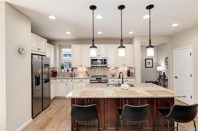8186 E 53rd Dr, Denver, CO 80238 - kitchen featuring stainless steel appliances, decorative backsplash, white cabinets, light wood finished floors, and recessed lighting
