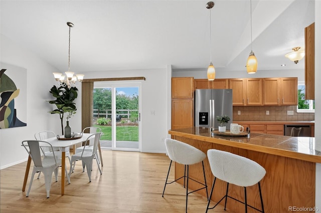 5193 Rustic Ave, Firestone, CO 80504 - kitchen with stainless steel appliances, a breakfast bar, backsplash, light wood finished floors, and a chandelier