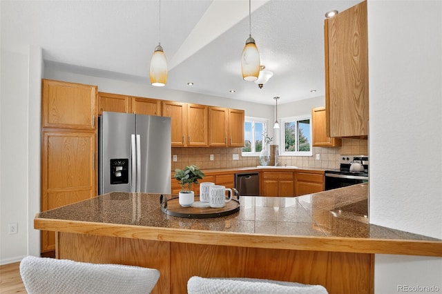 5193 Rustic Ave, Firestone, CO 80504 - kitchen with appliances with stainless steel finishes, backsplash, hanging light fixtures, a breakfast bar, and tile countertops