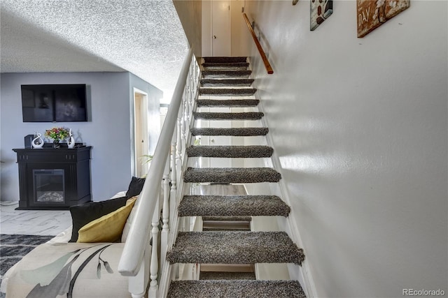 stairway featuring a textured ceiling