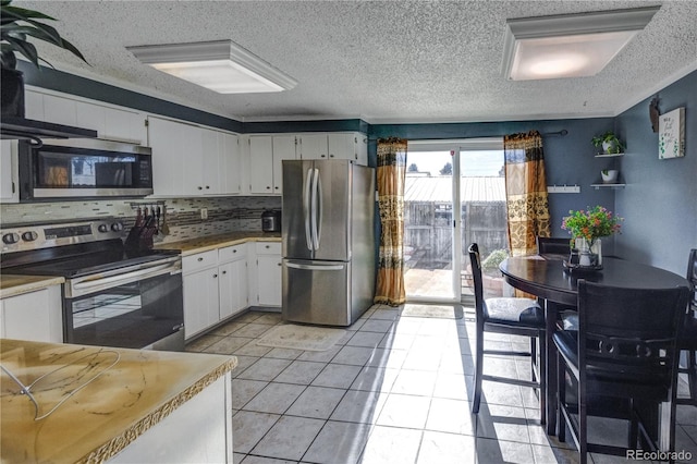 kitchen featuring white cabinets, a textured ceiling, decorative backsplash, light tile patterned floors, and appliances with stainless steel finishes