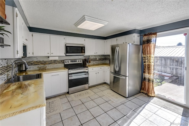 kitchen with appliances with stainless steel finishes, tasteful backsplash, sink, white cabinets, and light tile patterned flooring