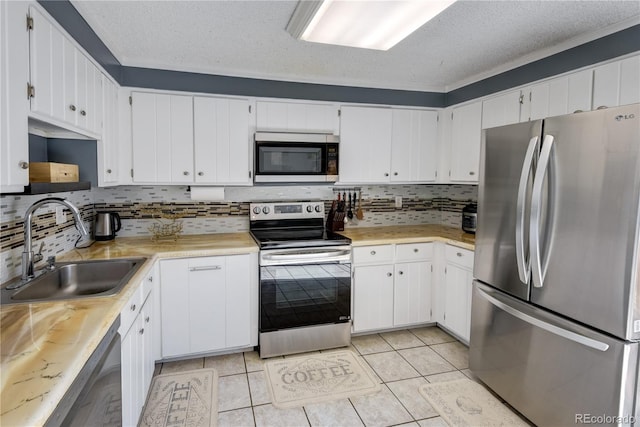 kitchen with appliances with stainless steel finishes, backsplash, a textured ceiling, sink, and white cabinetry