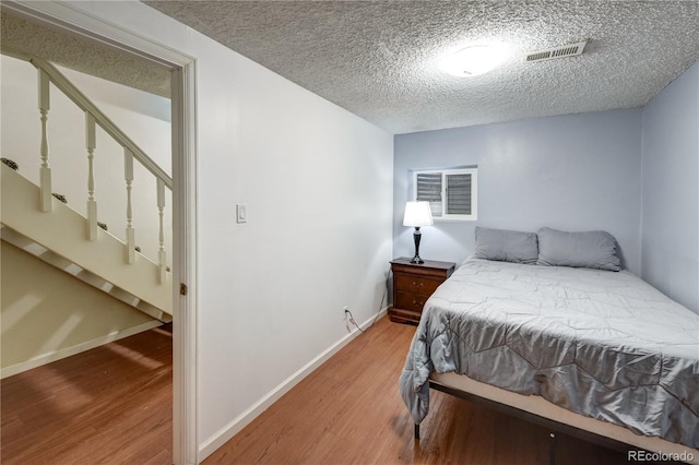 bedroom featuring wood-type flooring and a textured ceiling